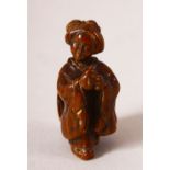 A JAPANESE MEIJI PERIOD CARVED WOOD NETSUKE OF A LADY - The lady stood with her hands together,