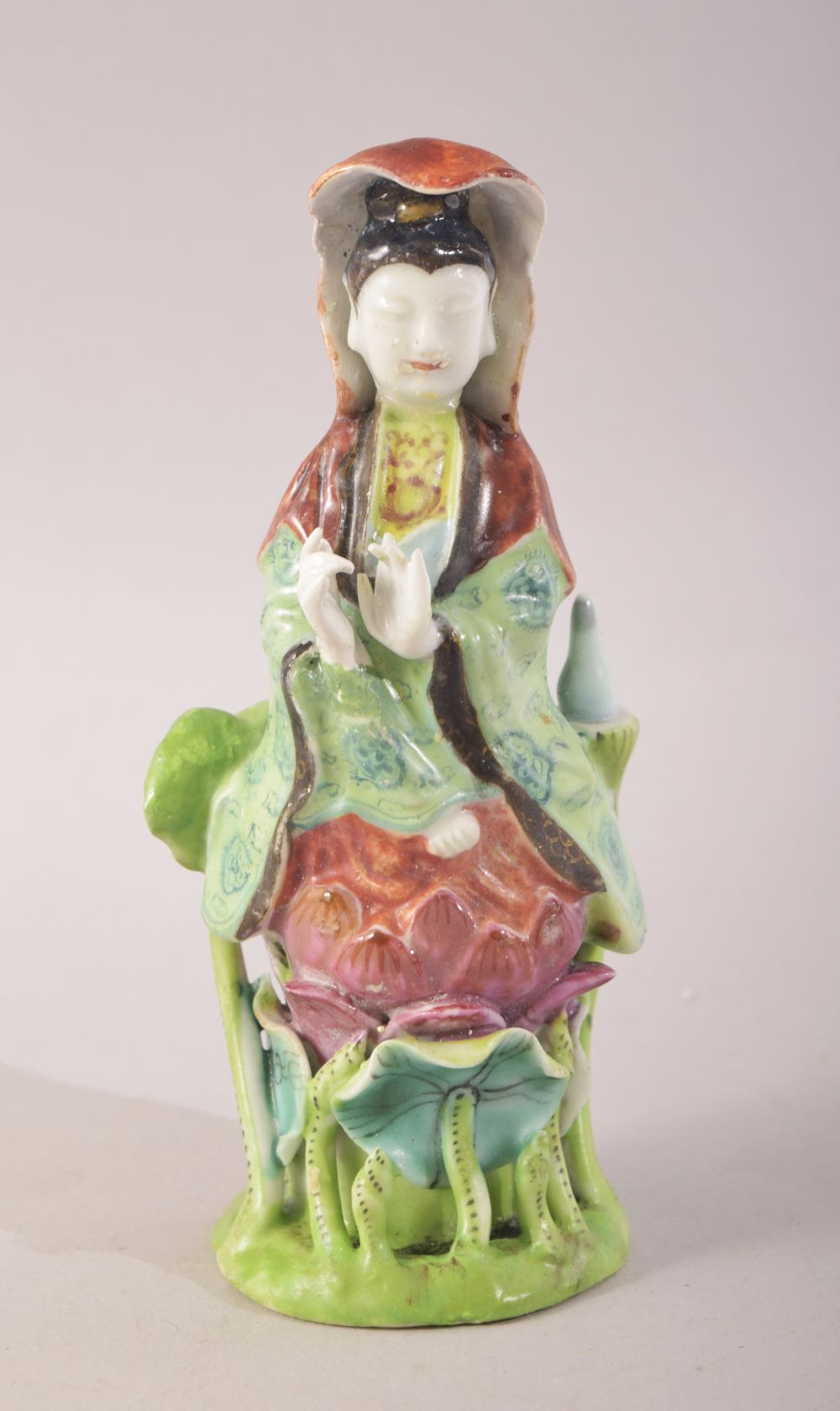 A SMALL CHINESE PORCELAIN FIGURE OF A FEMALE amongst lilies, 13cm high.