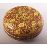 A CHINESE RED GROUND PORCELAIN CIRCULAR BOX AND COVER, painted with yellow dragons and flower