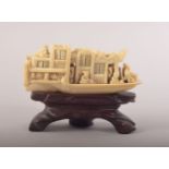 A SMALL CARVED IVORY MODEL OF A JUNK and wooden stand, 8cm long.