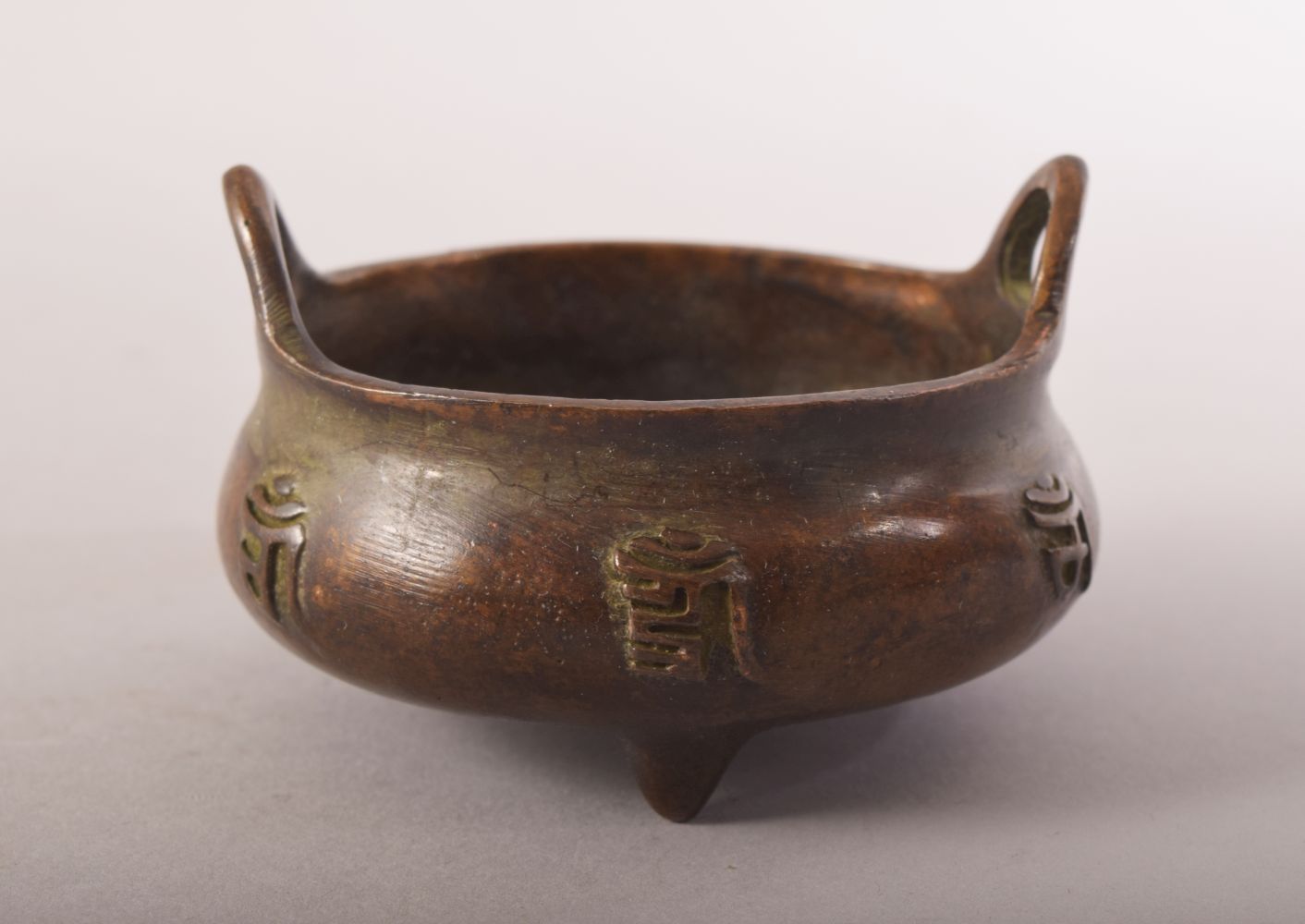 A SMALL CHINESE BRONZE TWIN HANDLE TRIPOD CENSER, impressed mark to base, 8cm diameter.