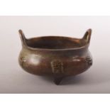 A SMALL CHINESE BRONZE TWIN HANDLE TRIPOD CENSER, impressed mark to base, 8cm diameter.