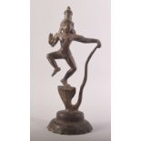 AN INDIAN BRONZE FIGURE OF A DEITY, possibly Krishna, stood upon a multi headed snake, 25cm high.