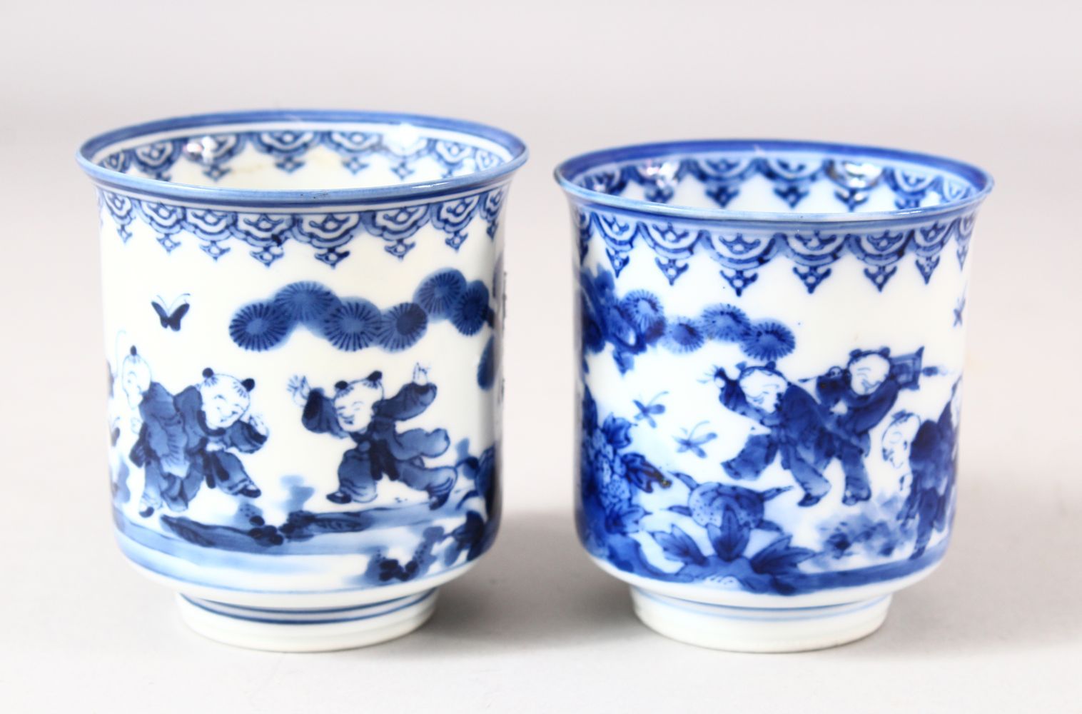 A NEAR PAIR OF JAPANESE BLUE AND WHITE PORCELAIN CUPS, decorated with boys in a landscape, 7.5cm and