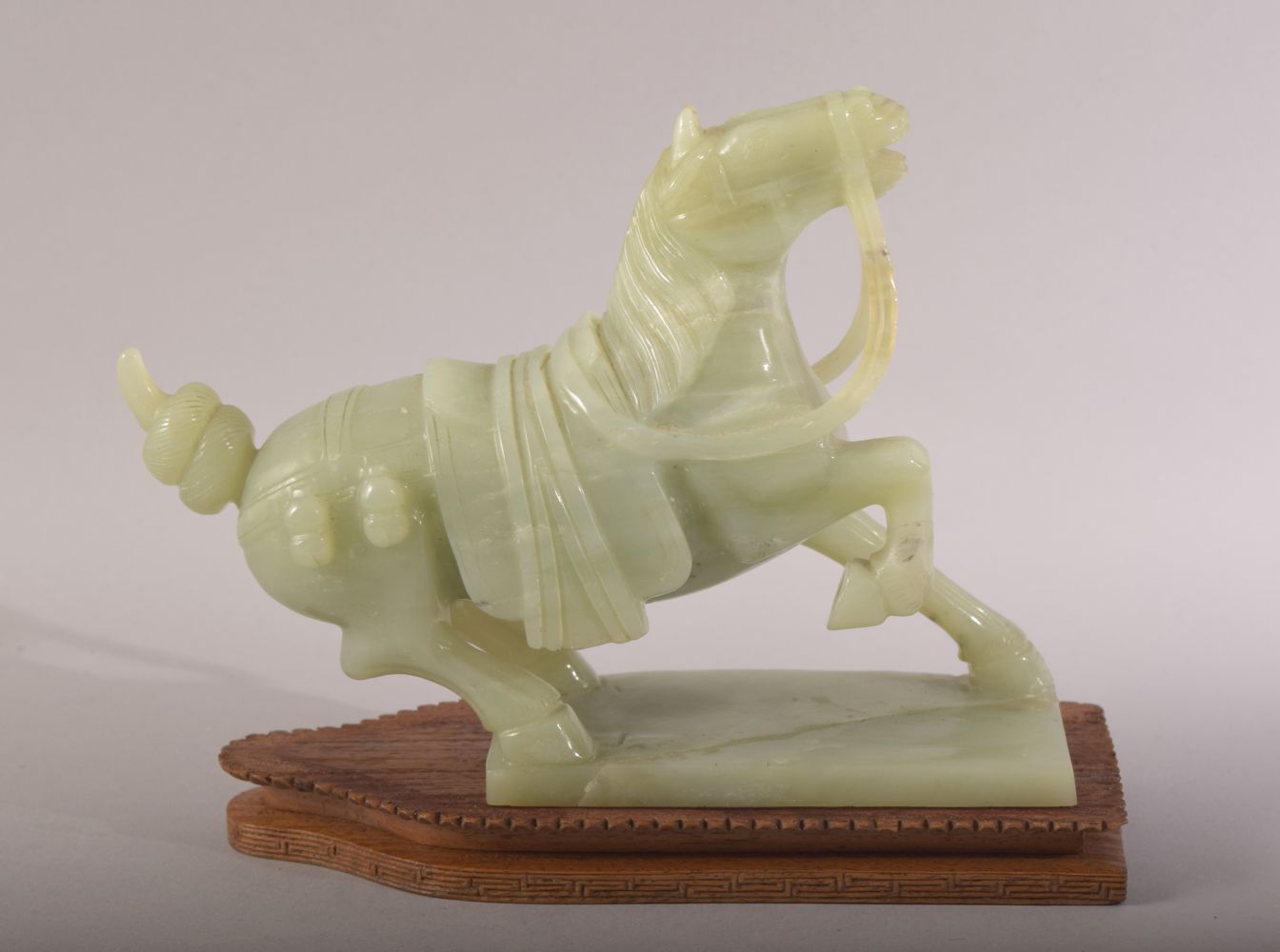 A CHINESE CARVED JADE MODEL OF A HORSE, with a wooden stand, figure 20cm long.