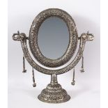 A GOOD INDIAN EMBOSSED WHITE METAL MIRROR ON STAND - the mirror with twin elephant heads