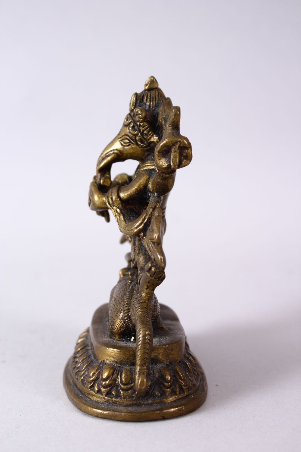 A SMALL INDIAN BRONZE FIGURE OF GANESH UPON BEAST, upon a stylized base, holding many implements. - Image 5 of 6