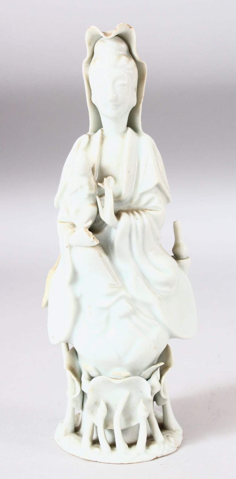 A CHINESE BLANC DE CHINE PORCELAIN FIGURE of guanyin upon lotus and lily pads, 22cm high.