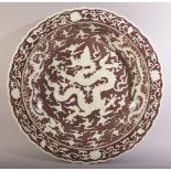 A LARGE CHINESE IRON RED UNDERGLAZED DRAGON DISH, decorated with a large dragon amongst stylised