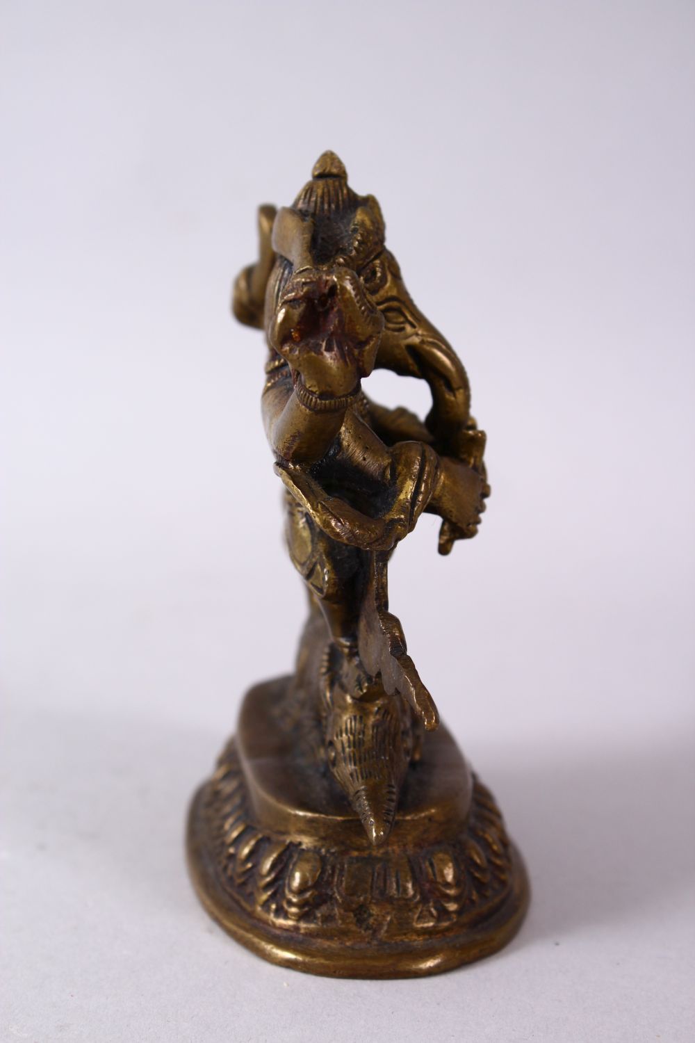 A SMALL INDIAN BRONZE FIGURE OF GANESH UPON BEAST, upon a stylized base, holding many implements. - Image 3 of 6