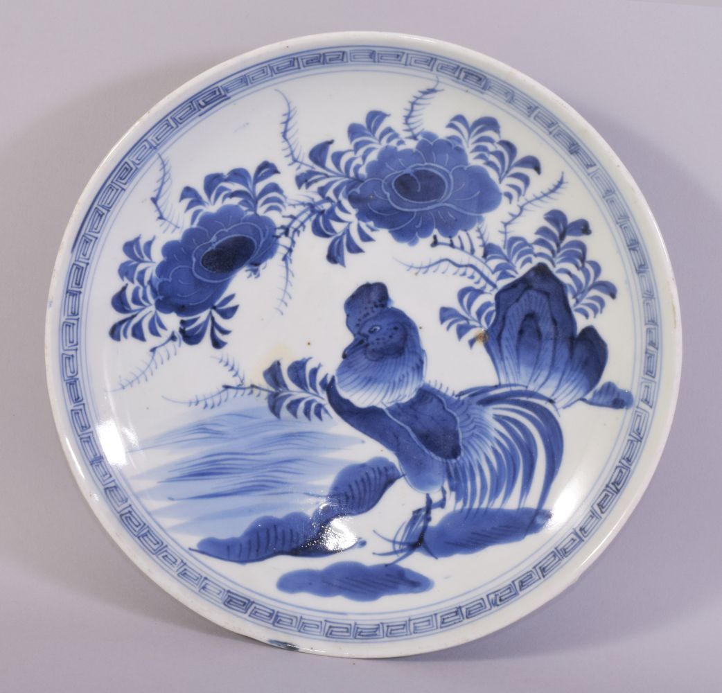 A CHINESE BLUE AND WHITE PORCELAIN DISH, painted with rooster and native flora, 27cm diameter.