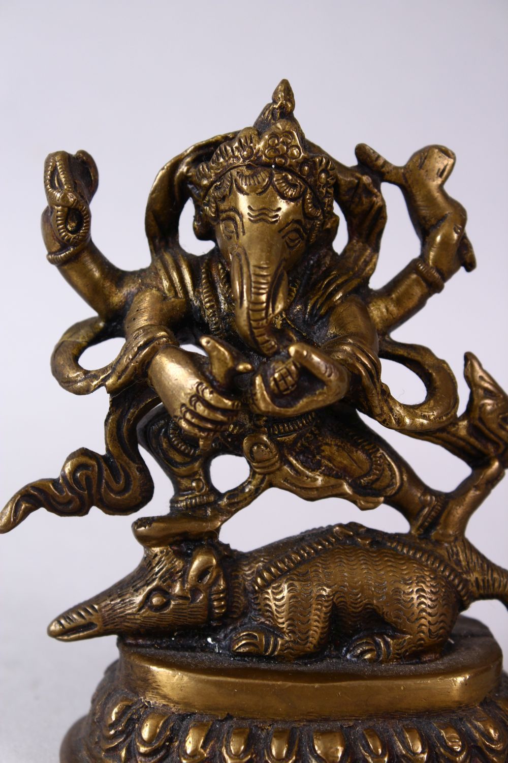 A SMALL INDIAN BRONZE FIGURE OF GANESH UPON BEAST, upon a stylized base, holding many implements. - Image 2 of 6