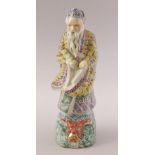 A CHINESE FAMILLE ROSE PORCELAIN FIGURE OF A SAGE, stood upon a wave formation with a mask of a