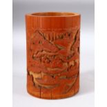 A CHINESE BAMBOO BRUSH POT, carved with a landscape scene and figures, 17cm high.