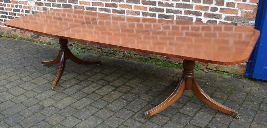 Regency style mahogany twin pedestal dining table on sabre legs with removable leaf extending to 2.