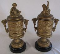 Pair of classical style gilt metal lidded urns decorated with cherubs and vines H 40 cm