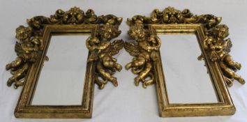 Pair of ornate gilt framed mirrors with cherub detail size approximately 44cm x 31cm at the widest