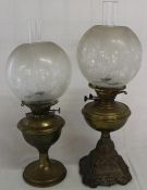 Two cast iron paraffin lamps with etched glass shades