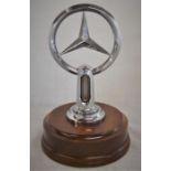 Genuine Mercedes-Benz radiator emblem with thermostat possibly of the 1950's on a turned mahogany