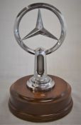Genuine Mercedes-Benz radiator emblem with thermostat possibly of the 1950's on a turned mahogany