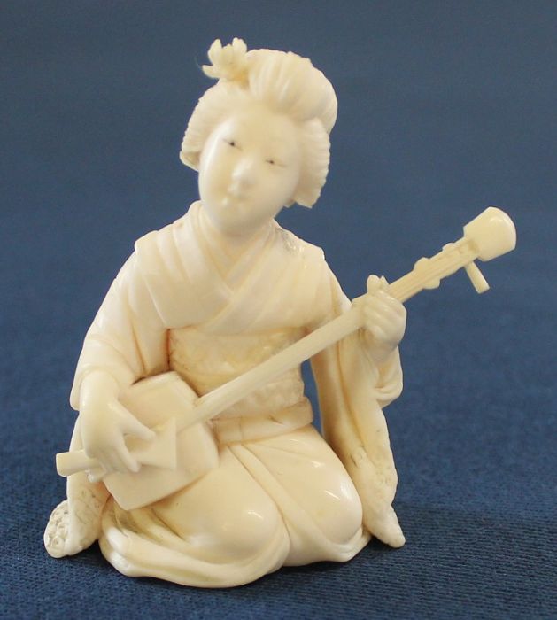 Small Japanese ivory okimono of a kneeling geisha playing a shamisen, approximately 5cm in height