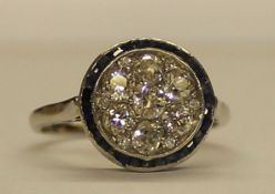 Early 20th century diamond circular plaque cluster ring surrounded by channel set sapphires,