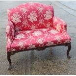 A 19th century carved mahogany two-seat settee of early Georgian design, upholstered in a red floral