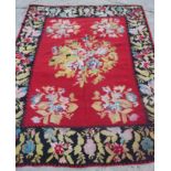 A vintage kelim carpet with floral design on a red ground and deep floral borders, 118" x 102"