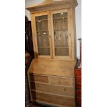 A stripped pine bureau bookcase enclosed two glazed doors over fall front and two short and three