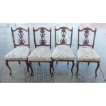 A set of four carved walnut framed side chairs with pierced panel backs and stuffed over seats, on