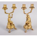 A pair of gilt metal candelabra with fauns holding a bird, on claw supports
