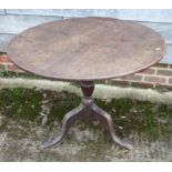 An early 19th century oak circular tilt top table, on baluster turned column and tripod splay