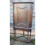 A 19th century oak corner cupboard enclosed panel door, on stand with turned and stretchered