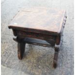 A carved elm stool of 16th century design, on panel end supports, 16" wide x 12" deep x 16" high