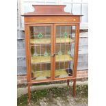 An Edwardian walnut and inlaid ledge back display cabinet enclosed leaded glazed doors, on square