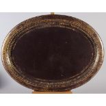A 19th century Persian oval papier-mache tray with gilt arabesque patterned border, retailed by W