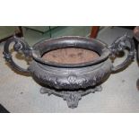 A cast iron oval two-handle planter, 24" wide x 13" high, and a cast iron urn (cracked) with lion