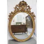 A 19th century gilt framed oval wall mirror with Rococo scrolled and floral pediment and egg and