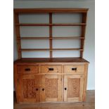 A waxed pine dresser with open shelves over three drawers and three cupboards, on block base, 62"