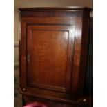 A Georgian oak and mahogany banded corner hanging cupboard, interior fitted shaped shelves