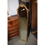 A gilt framed slip mirror with arch top and leaf decoration, plate 46" x 9 1/2"