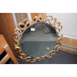 A gilt framed wall mirror with open scroll work decoration, bevelled plate 18" dia
