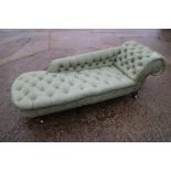 A chaise longue, button upholstered in a green brocade, on turned supports, 72" wide