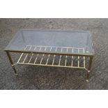 A brass frame and smoked glass low coffee table, 36" long x 18" deep x 60" high, and a pair of