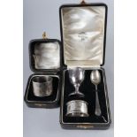 A silver christening set, comprising an egg cup, a spoon and a matched napkin ring, and a cased