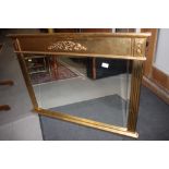 A gilt framed overmantel mirror with scroll decoration and reeded side panels, bevelled plate, 23" x