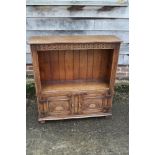 A carved oak open bookcase over cupboard enclosed two doors, on stile supports, 33" wide x 10"