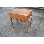An oak sewing table, on stretchered and castored supports, 22" wide