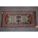 A Kazak rug with two blue medallions on a red ground, 42" x 20" approx