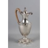 An 18th century silver pedestal hot water jug with acorn finial, acanthus and laurel leaf decoration